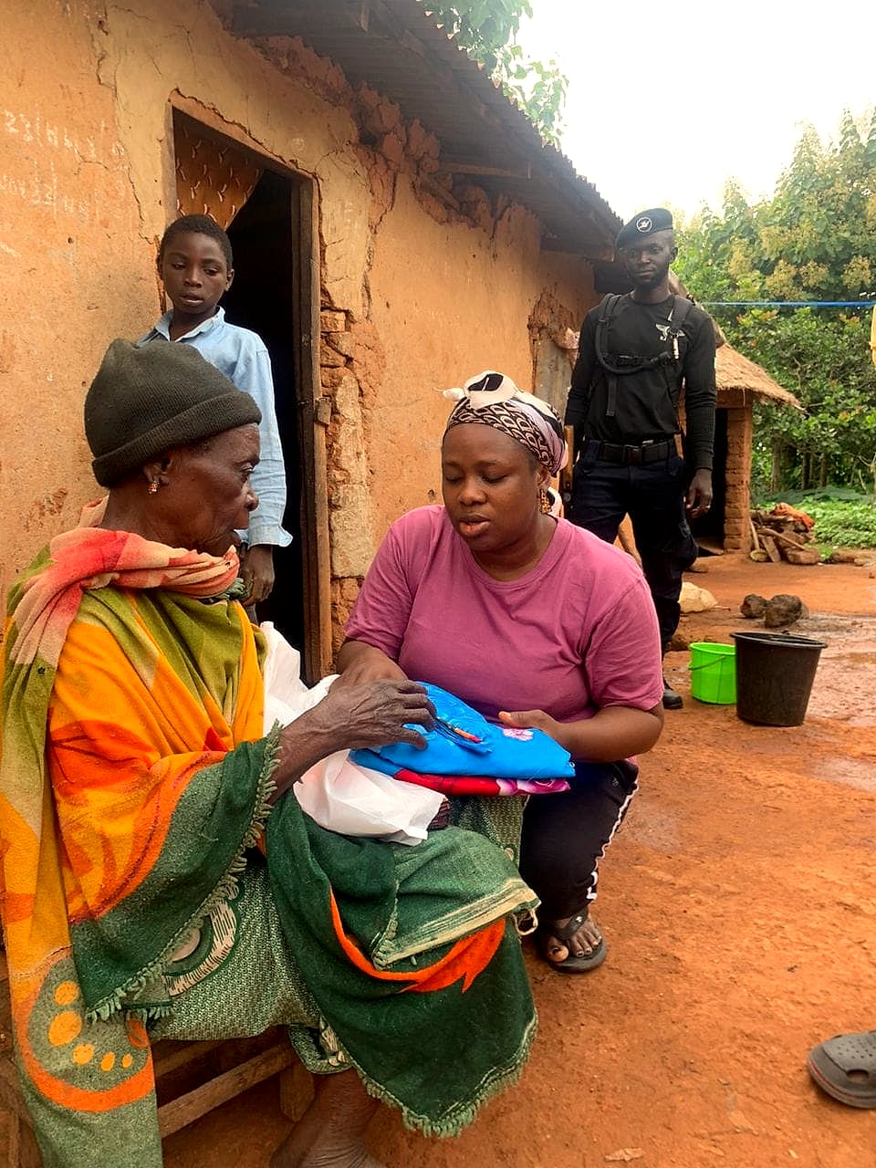 A volunteer presenting new clothing to an elderly woman