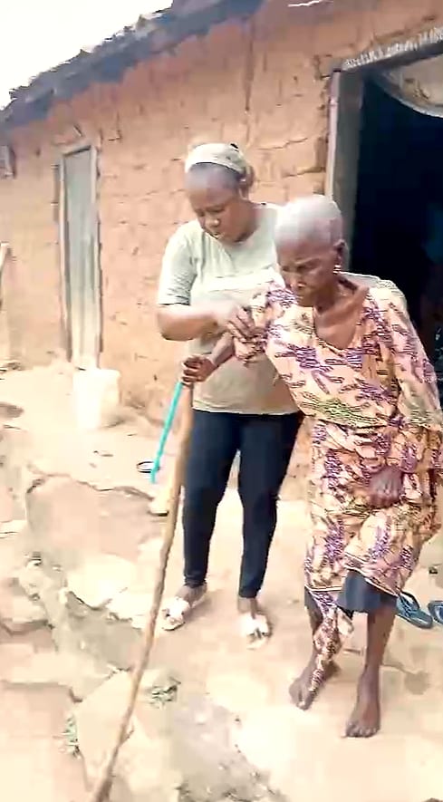 A volunteer helping an elderly woman walk