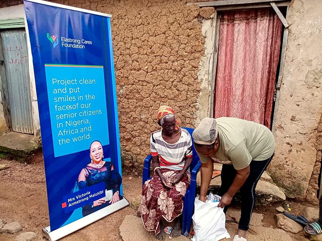 A volunteer serving an elderly woman beside the Elastrong Cares banner